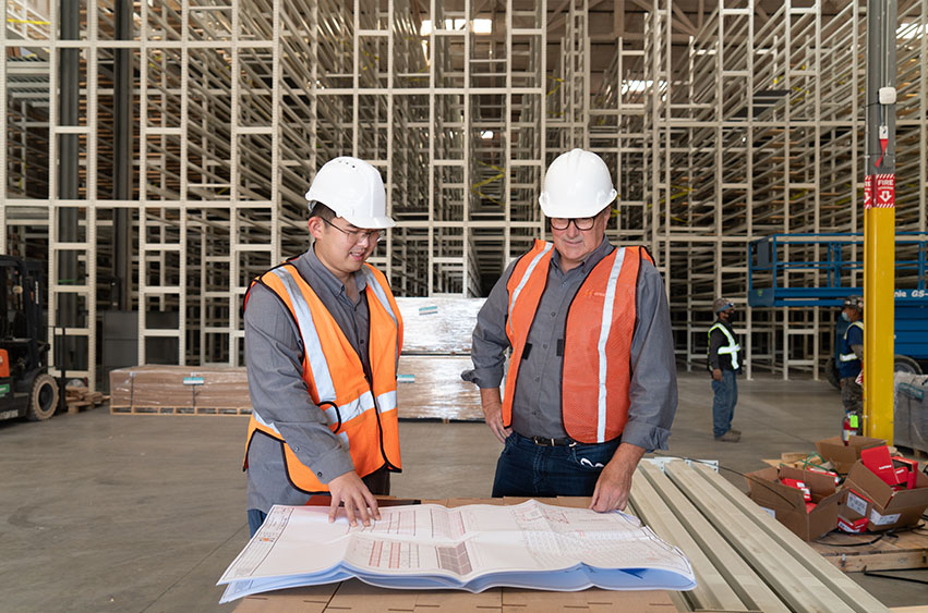 Ricky Yu reviewing warehouse rack layout plans on a jobsite