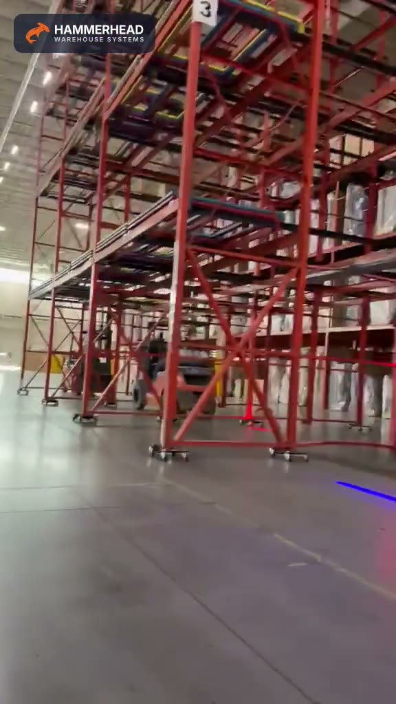 Assembled push-back rack bays standing on caster dollies in a warehouse aisle with a forklift alongside